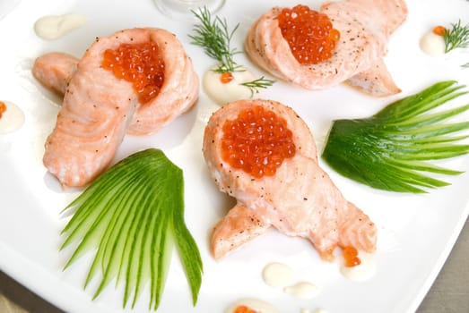roasted salmon filet with red caviar, cucumbers and sauce