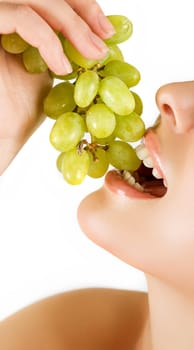 Closeup of woman mouth with green grapes on a white