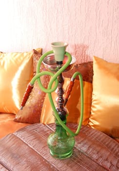 Green hookah over yellow pillows and decorations