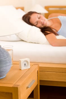 Alarm clock on bedside table woman sleeping in white bed