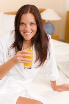 Breakfast - Smiling woman with fresh orange juice in white bedroom
