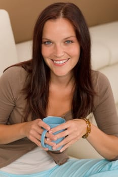 Attractive young woman at modern home sitting sofa drink coffee