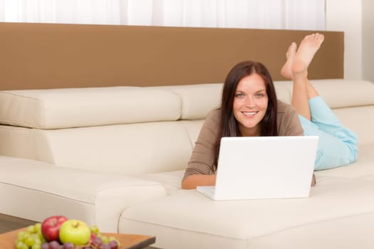 Attractive woman with laptop lying modern leather sofa living room