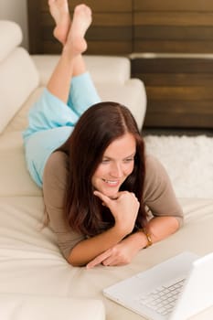 Attractive woman with laptop lying modern leather sofa living room