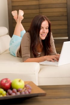 Attractive woman with laptop lying modern leather sofa living room