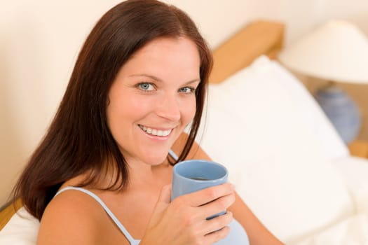 Bedroom - young woman drink coffee lying in white bed