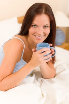 Bedroom - young woman drink coffee lying in white bed