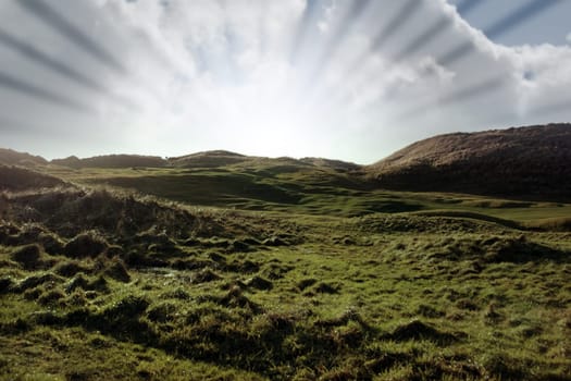 golfers playering and on a hole on a links golf course in ireland with sun rays in background