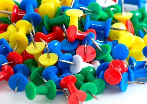 Many drawing-pins are photographed close-up on white background