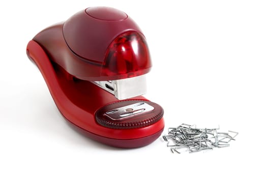 Stapler of red color are photographed near the paper-clips