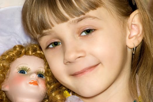 The girl has nestled on a doll and smiles