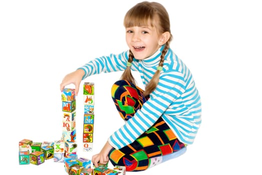 The little girl smiles and  plays with bricks