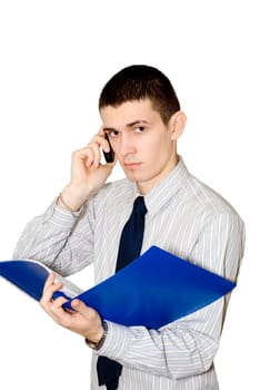 The young man holds in a hand a blue folder with documents and speaks by mobile phone