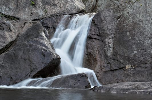 A waterfall over stone emptying into calm water below