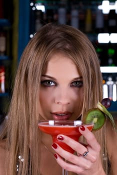 Beauty young woman portrait with a glass drinking a cocktail at a bar
