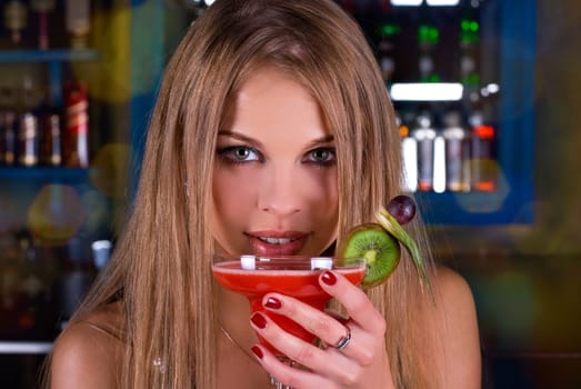 Beauty young woman portrait with a glass drinking a cocktail at a bar