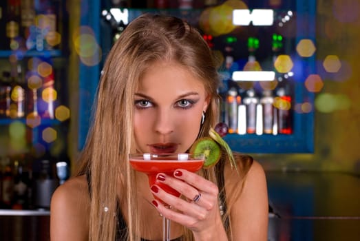 Beauty young woman portrait with a glass drinking a cocktail at a bar