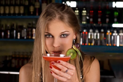 Beauty young woman portrait with a glass drinking a cocktail at a bar