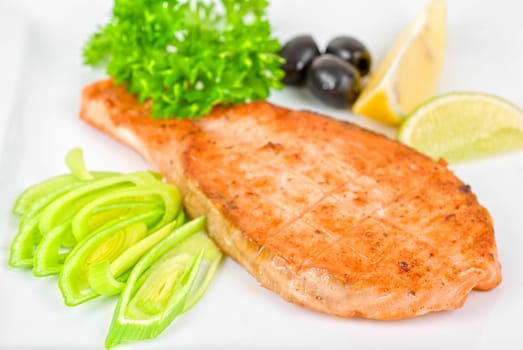 Grilled salmon steak with greens,onion, lemon, lime and olive