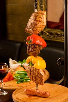 Big tasty roasted meat cuts at skewer on a decorated table