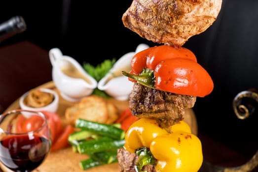 Big tasty roasted meat cuts at skewer on a decorated table