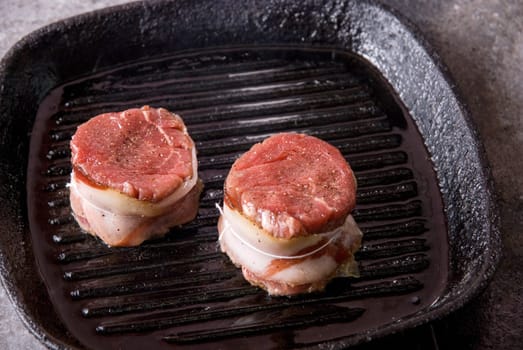Tasty beef steak grilling in a cast-iron ribbed fry pan