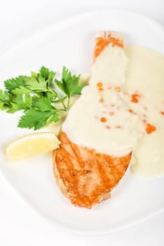 Grilled salmon steak with cheese sauce, greens, lemon and red caviar