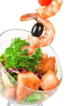 Fried kebab of shrimps with vegetables, greens and salmon fish