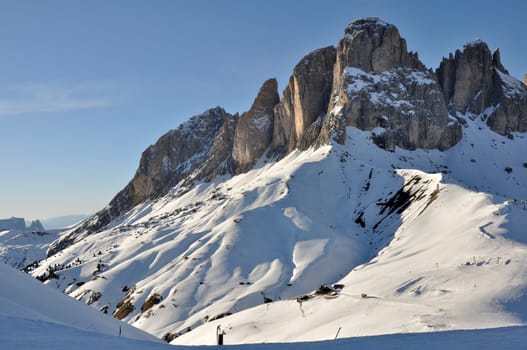 view of famous mountain in dolomites with steep cliffs and snowy slopes, shot at sunset in bright winter light
