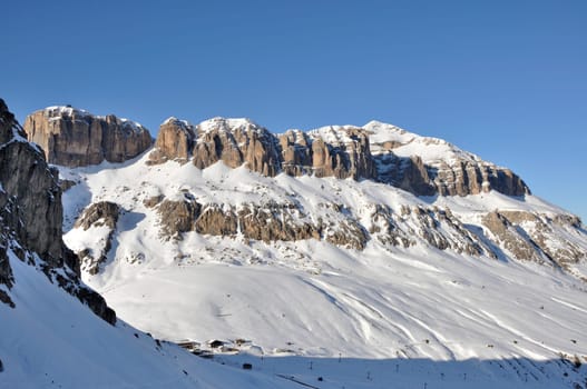 view of famous group in dolomites with steep cliffs and snowy slopes, shot in bright winter light from the east side of the mountain