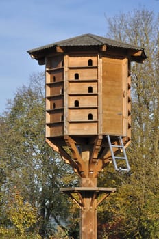 big artificial nest in urban park,  a wooden artificial apartment block for birds