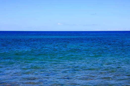 Blue sea with barely cloudy sky