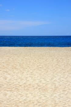 Sandy beach with blue sea and sky in portrait format