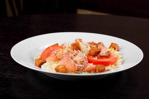 Salad of lettuce, chinese cabbage, tomato, garlic rusk, parmesan cheese, sauce and smoked salmon filet