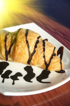 Fresh croissant at white plate, closeup photo