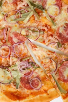 pizza closeup with smoked meat, salami, gherkin, onion and mozzarella cheese