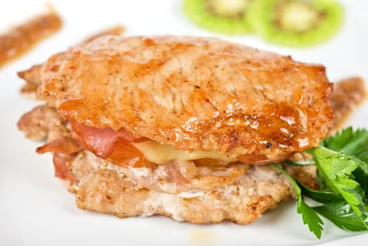 Cooked pork chop with kiwi and parsley on a white