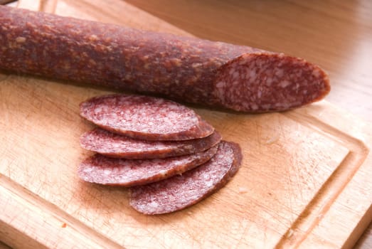 An salami with sliced pieces at table
