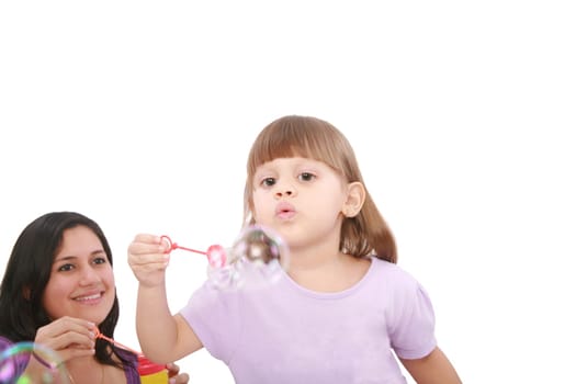 Portrait of funny lovely little girl blowing soap bubbles with her mom. Little girl on focus.
