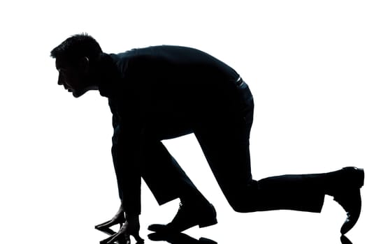 one caucasian man in starting block posture ready to run full length silhouette in studio isolated white background