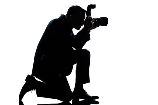 one caucasian man kneeling photographer full length silhouette in studio isolated on white background