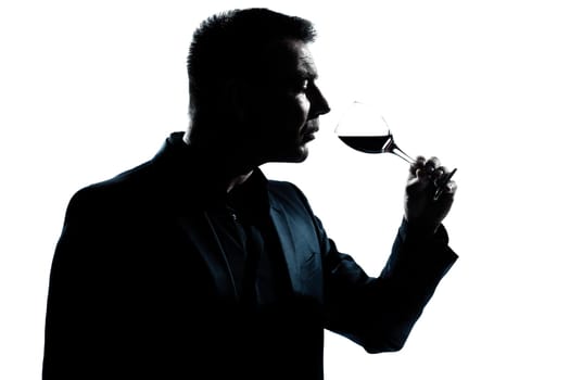 one caucasian man portrait silhouette smelling red wine glass in studio isolated white background