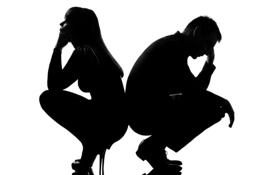 one sad caucasian couple man and woman crouching back to back in studio silhouette isolated on white background