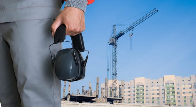 protective headphone at man hands on building background