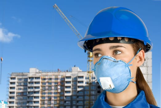 Builder pretty girl at helmet on a building background