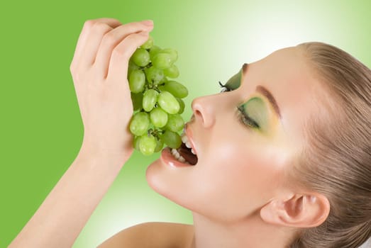 Pretty young woman with grape closeup on the green background