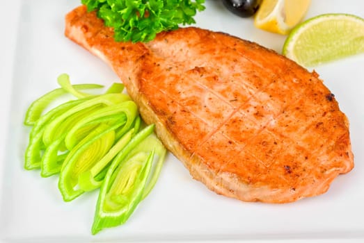 Grilled salmon steak with greens,onion, lemon, lime and olive