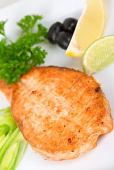 Grilled salmon steak with greens,onion, lemon, lime and olive