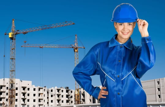 Builder pretty girl at helmet on a building background