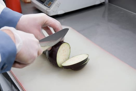 Cook cutting a zucchini at kitchen board